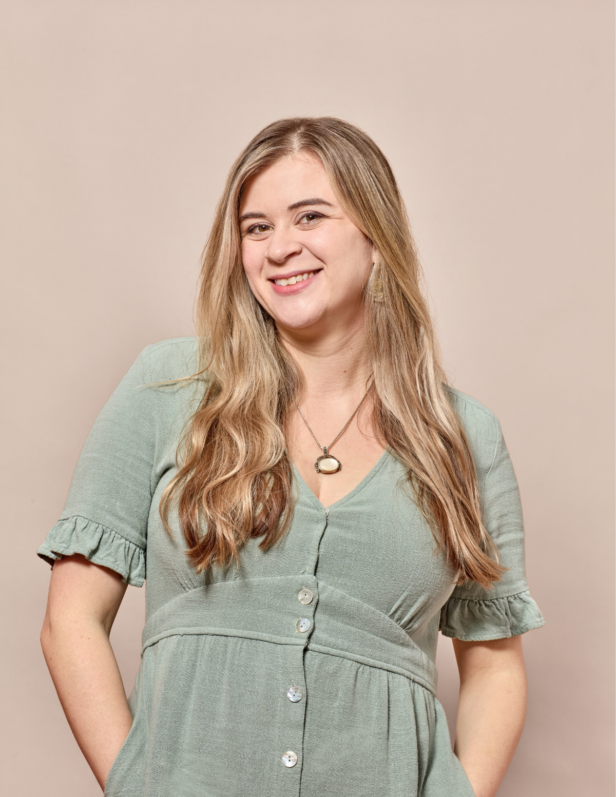 Erica Catherine wearing a green dress against a beige background