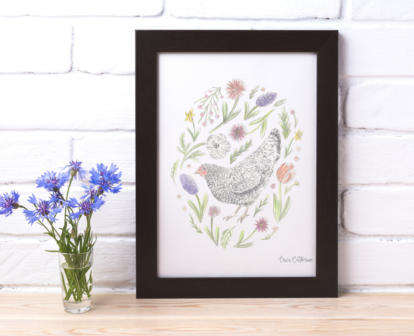 Framed artwork of a chicken surrounded by flowers on a white brick wall background.