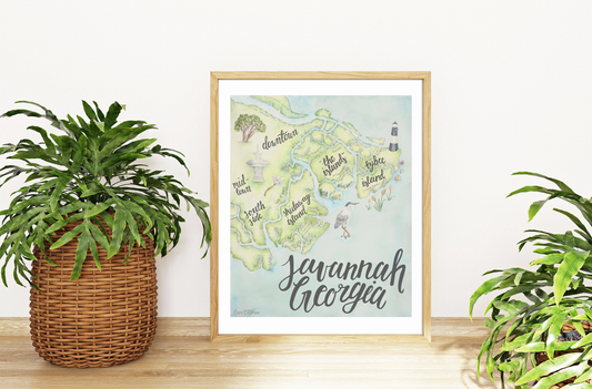 Framed map of Savannah, Georgia on a wall with plants on either side.