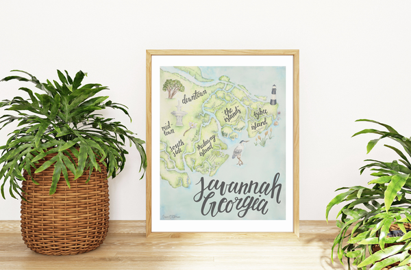 Framed map of Savannah, Georgia on a wall with plants on either side.