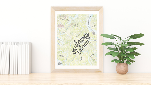 Framed map print of Skidaway Island on a wooden surface with a plant and books in the background.