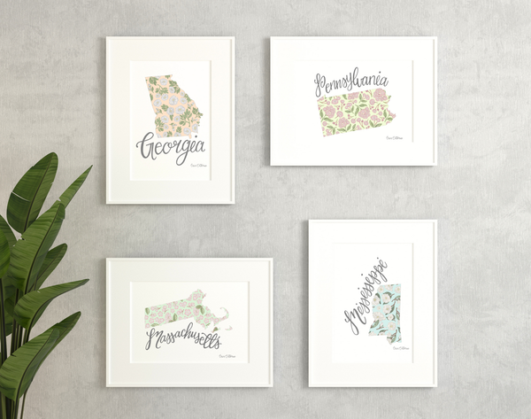 Set of four framed prints with floral state illustrations on a gray wall.