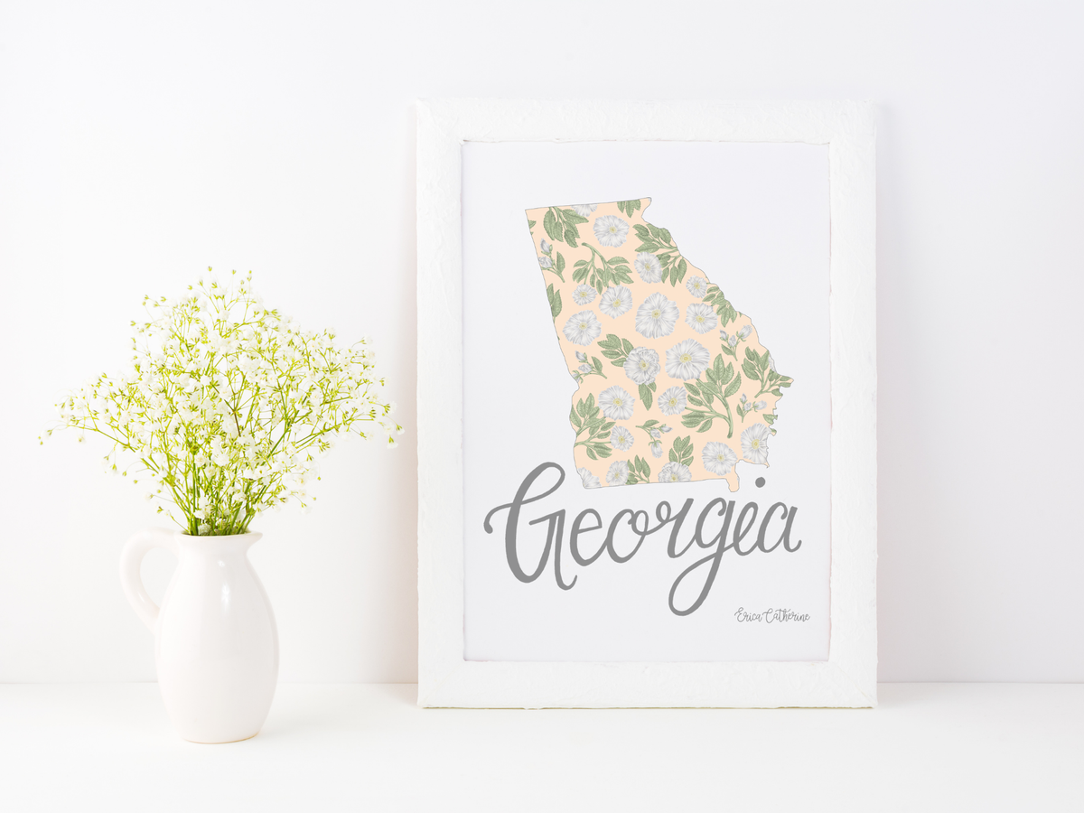 Framed artwork of a floral map of Georgia with 'Georgia' text on a white surface.