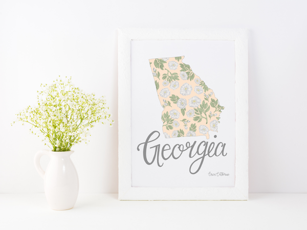 Framed artwork of a floral map of Georgia with 'Georgia' text on a white surface.