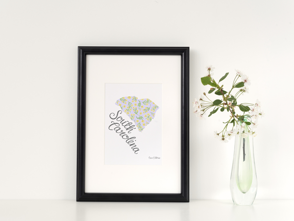 Framed artwork of South Carolina with a vase of flowers on a white background